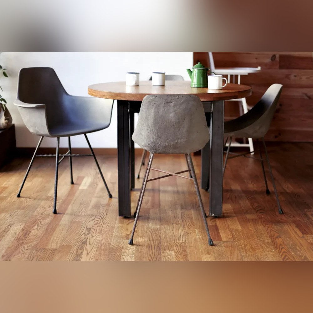 Fauteuil en béton Hauteville au bout d'une table ronde en bois avec deux chaises en béton sans accoudoirs