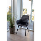 Fauteuils Harbo noirs autour table bois pieds croisés dans salon lumineux baies vitrées