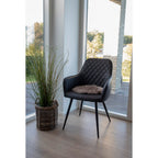 Gros plan fauteuil Harbo noir matelassé avec coussin décoratif fourrure beige