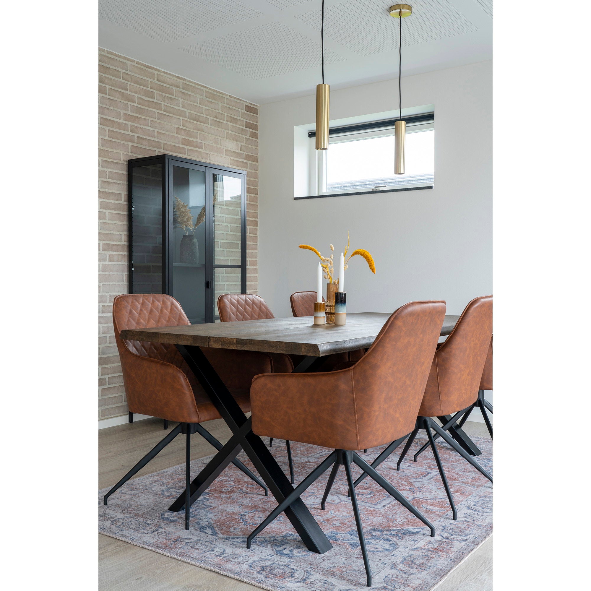 Fauteuils Harbo pivotants cuir vintage brun autour table bois salle à manger avec suspension dorée vitrine et tapis persan