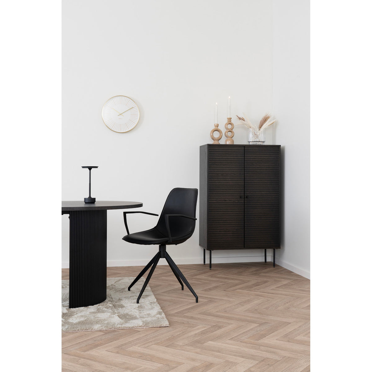 Fauteuil Monaco total look noir avec accoudoirs devant une table ronde noire dans intérieur minimaliste