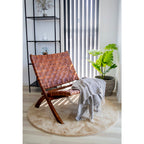 Fauteuil Perugia cuir tressé cognac dans un coin lecture lumineux avec tapis rond et plante tropicale