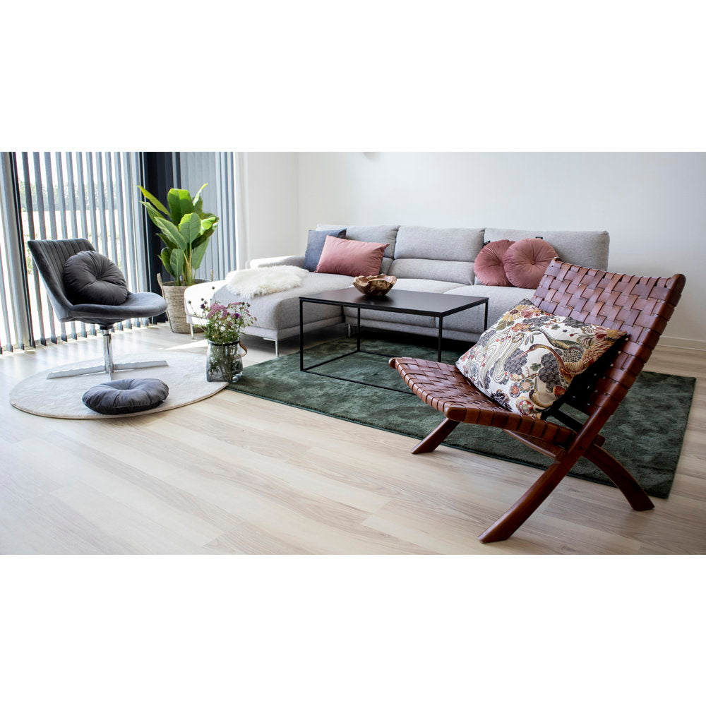 Fauteuil pliant Perugia cuir tressé cognac dans un salon contemporain avec canapé gris et tapis vert