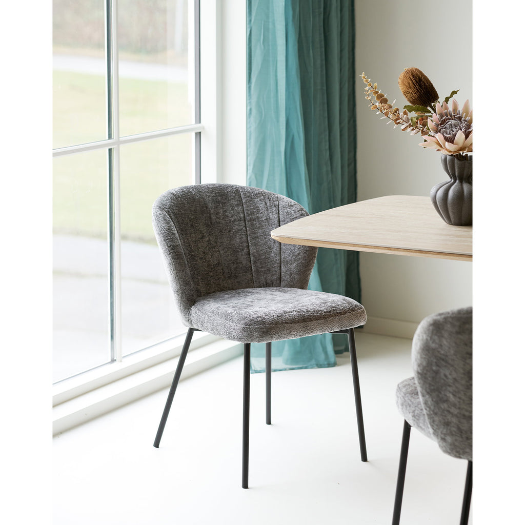 Fauteuil Roanne chenille gris posé près d'une table en chêne dans un espace repas lumineux contemporain