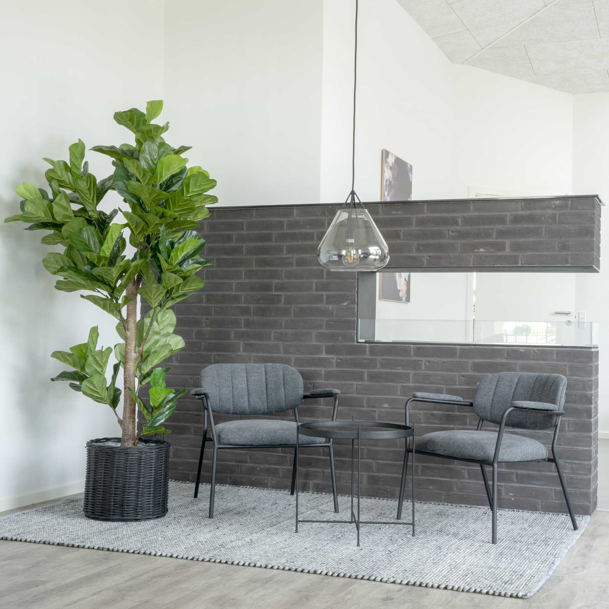 Ficus lyrata artificiel vert dans panier rotin noir espace industriel brique avec fauteuils gris