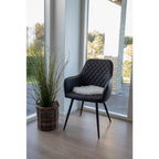 Galette fausse fourrure blanche posée sur fauteuil noir capitonné ambiance scandinave