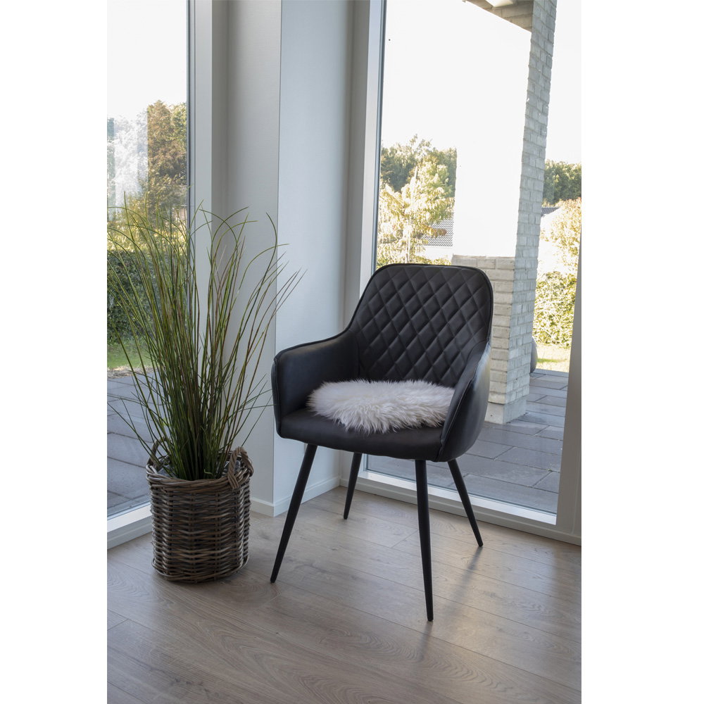 Galette vraie peau d'agneau ivoire posée sur fauteuil noir capitonné ambiance scandinave lumineuse
