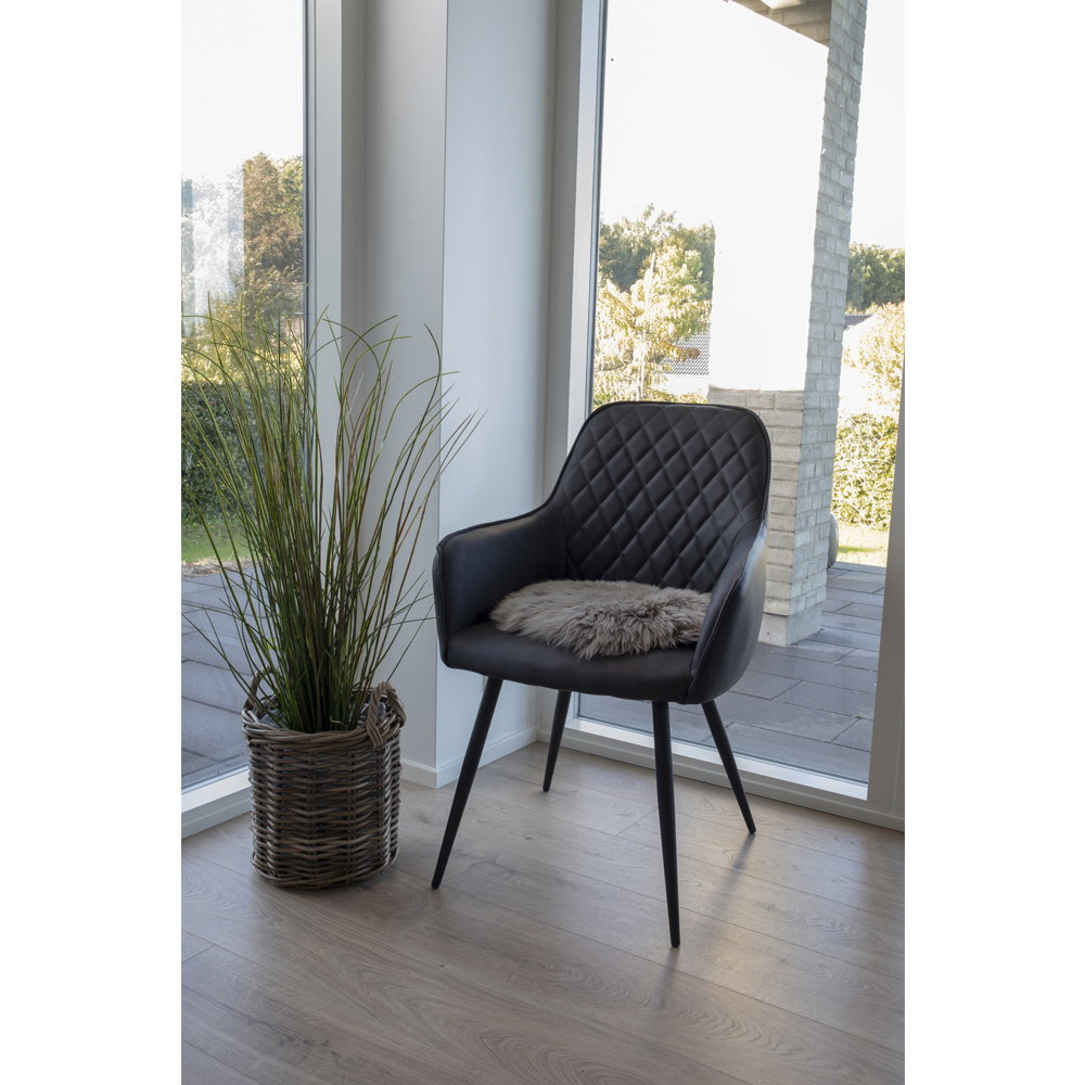 Galette vraie peau d'agneau mushroom posée sur fauteuil noir capitonné ambiance scandinave