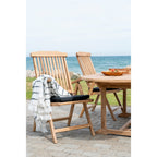 Galette Alture noire sur une chaise pliante en bois à accoudoirs avec un plaid blanc rayé