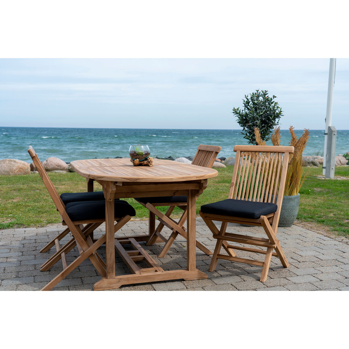 Galettes Alture noires sur des chaises pliantes en bois autour d'une table ovale au bord de la mer