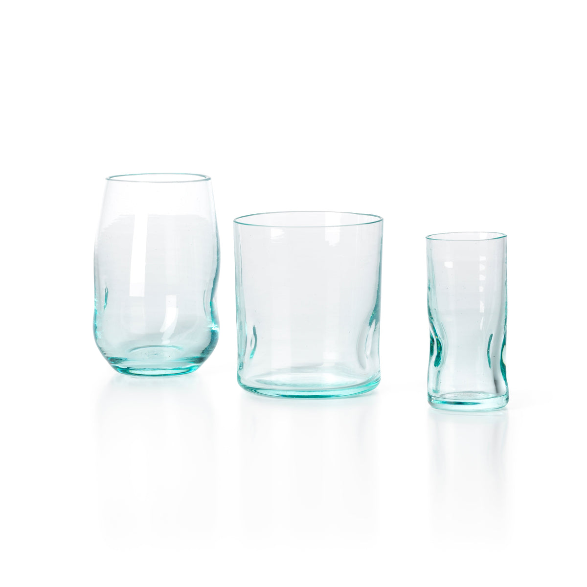 Gobelet galbé en verre recyclé bleuté à gauche d'un gobelet droit et d'un petit verre de la même teinte