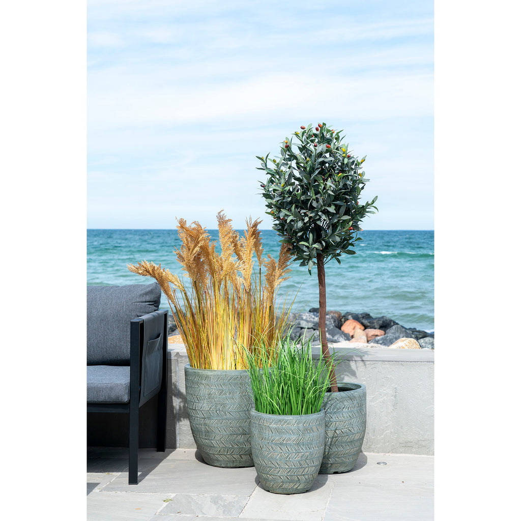 Graminée Poa artificielle verte dans pot céramique gris texturé terrasse bord de mer avec plantes et lanterne