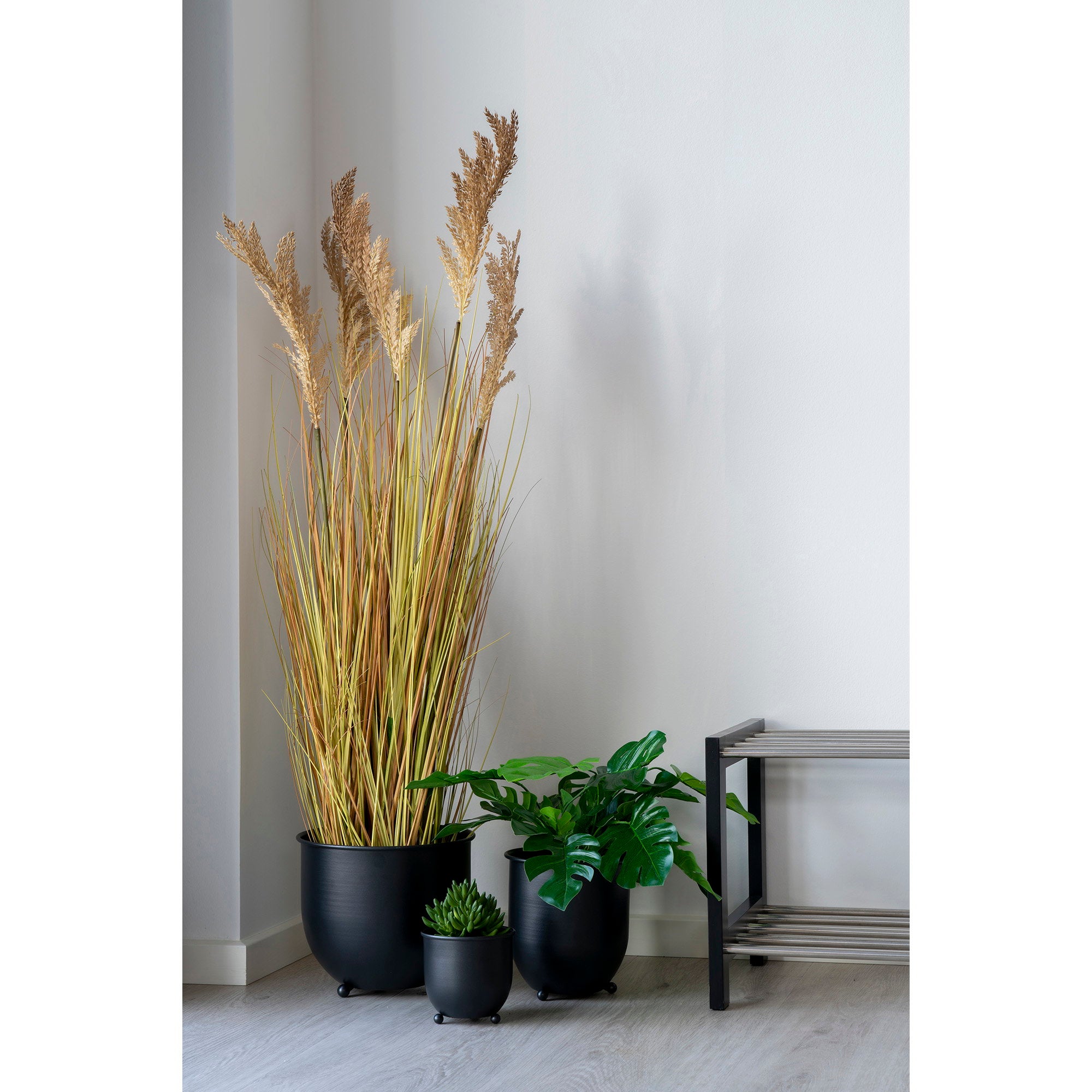 Graminée Sorghum artificielle dans cache-pot métal noir composition végétale avec monstera et plantes vertes