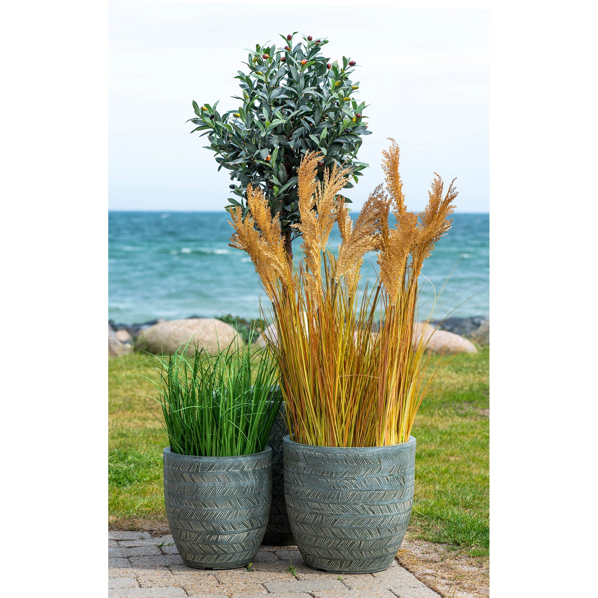 Graminée Sorghum artificielle dans pots céramique gris texturés terrasse bord de mer avec arbres artificiels