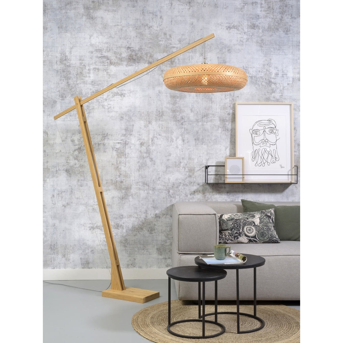 Lampadaire Palawan en bambou naturel au-dessus d'un canapé gris et de tables gigognes noires sur un tapis rond