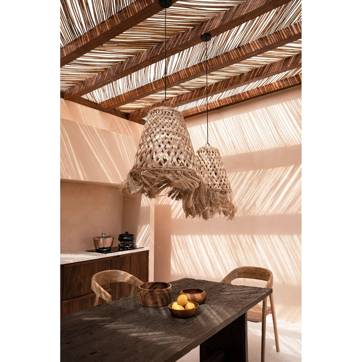 Grand saladier en bois de suar sur une table de repas dans une cuisine ouverte sous une pergola