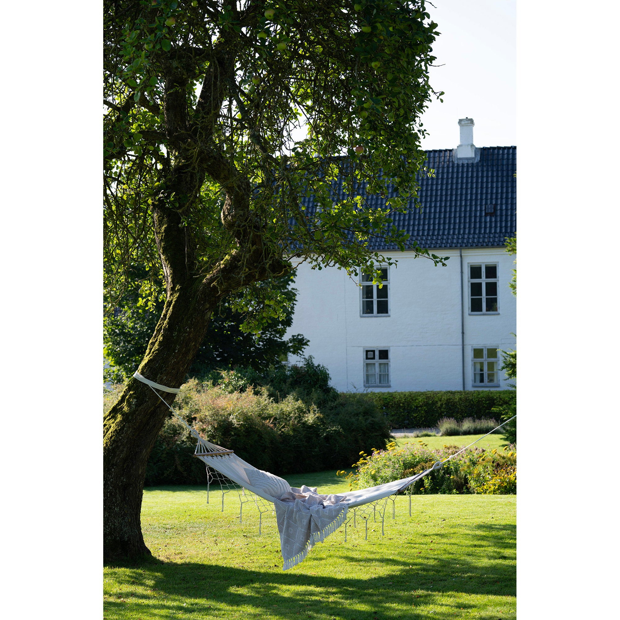 Hamac Edessa coton blanc cassé suspendu dans jardin verdoyant ambiance estivale