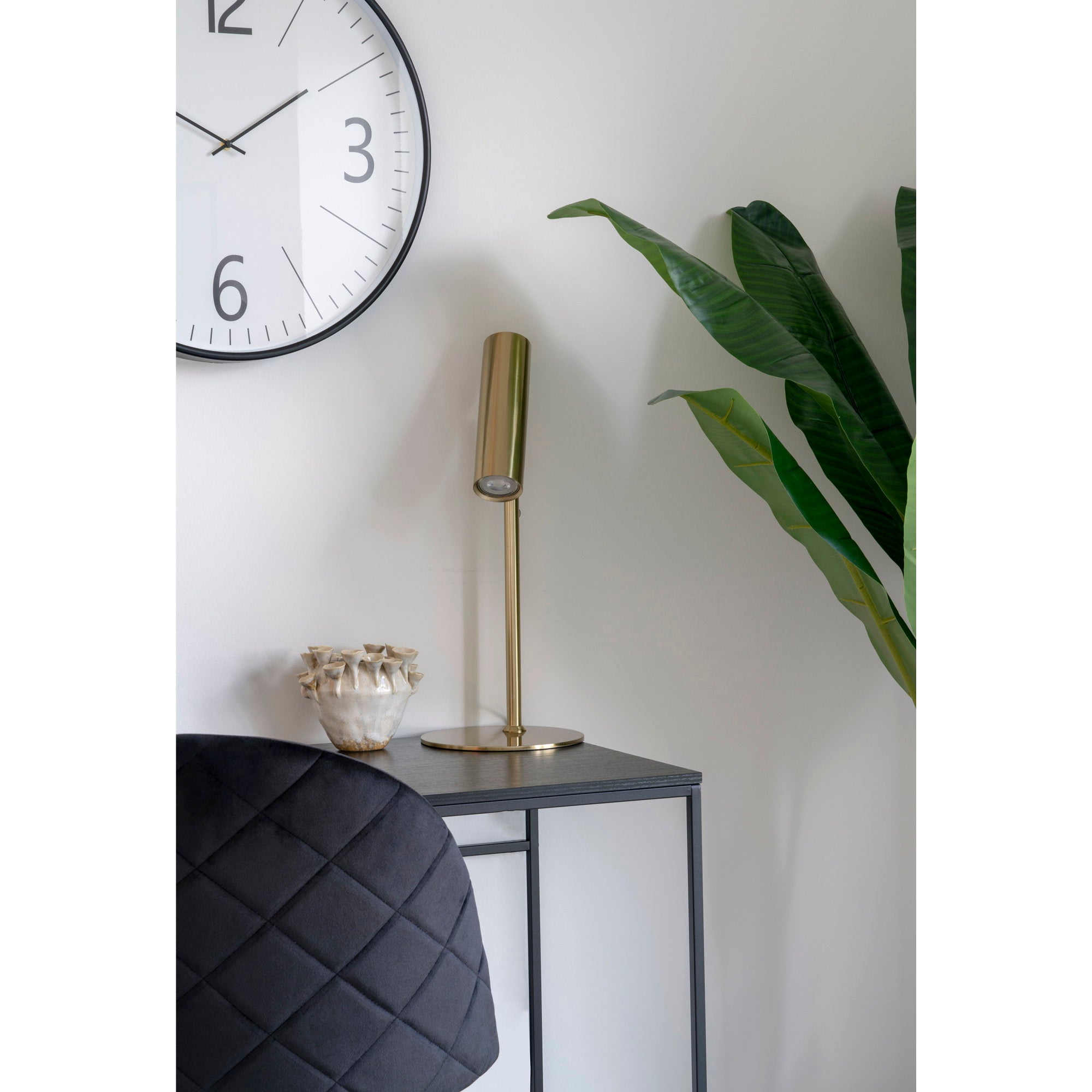 Détail horloge Biel noir blanc grand format au-dessus d'un bureau noir lampe laiton doré