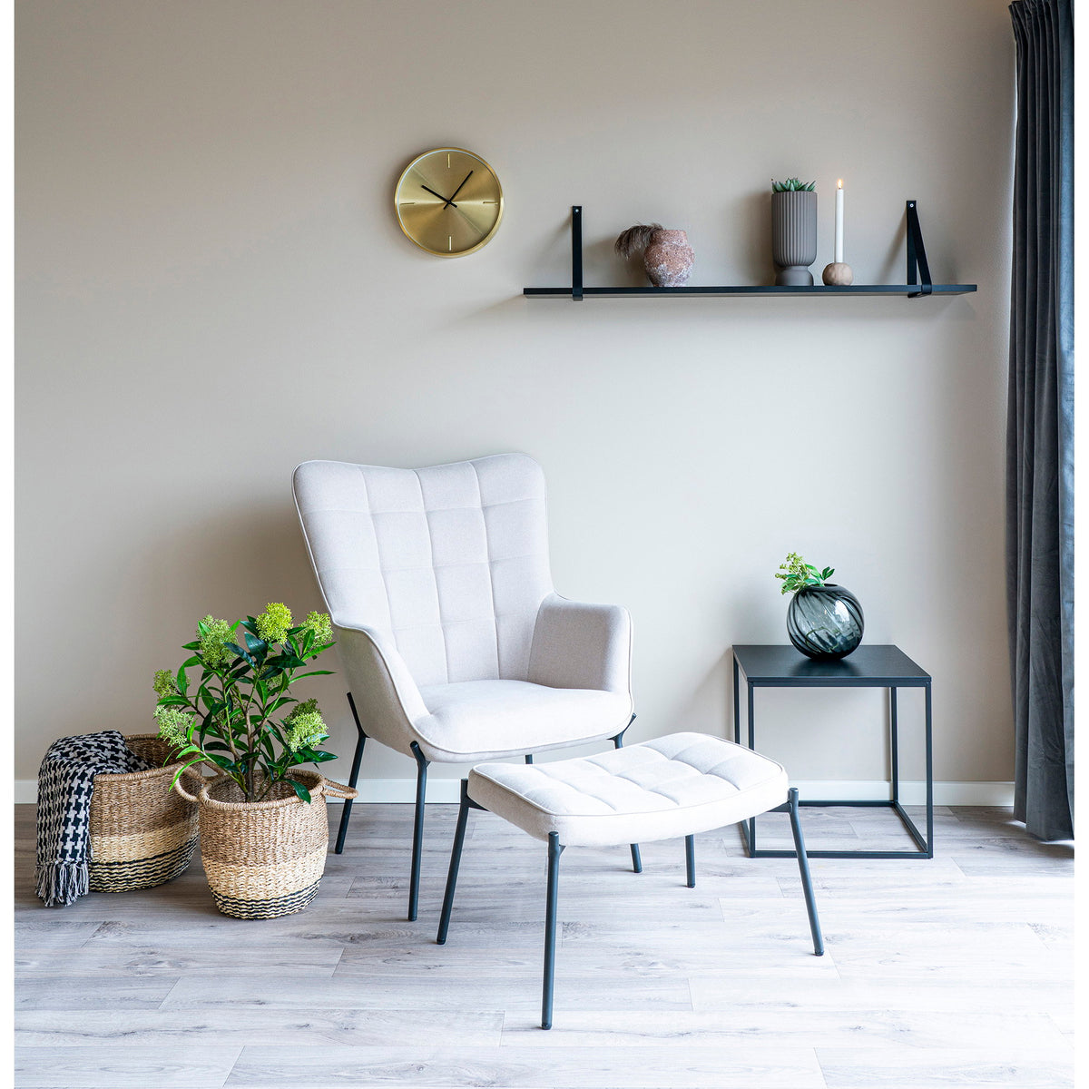 Horloge murale Istanbul dorée sur un mur beige au-dessus d'un fauteuil clair et de son repose-pieds