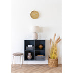 Horloge Rosolini ocre au-dessus d'une étagère murale à quatre cases bleu-gris surmontée d'une lampe