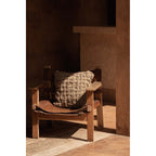 Coussin Crosier en lin naturel tressé posé sur un fauteuil en bois ancien au soleil