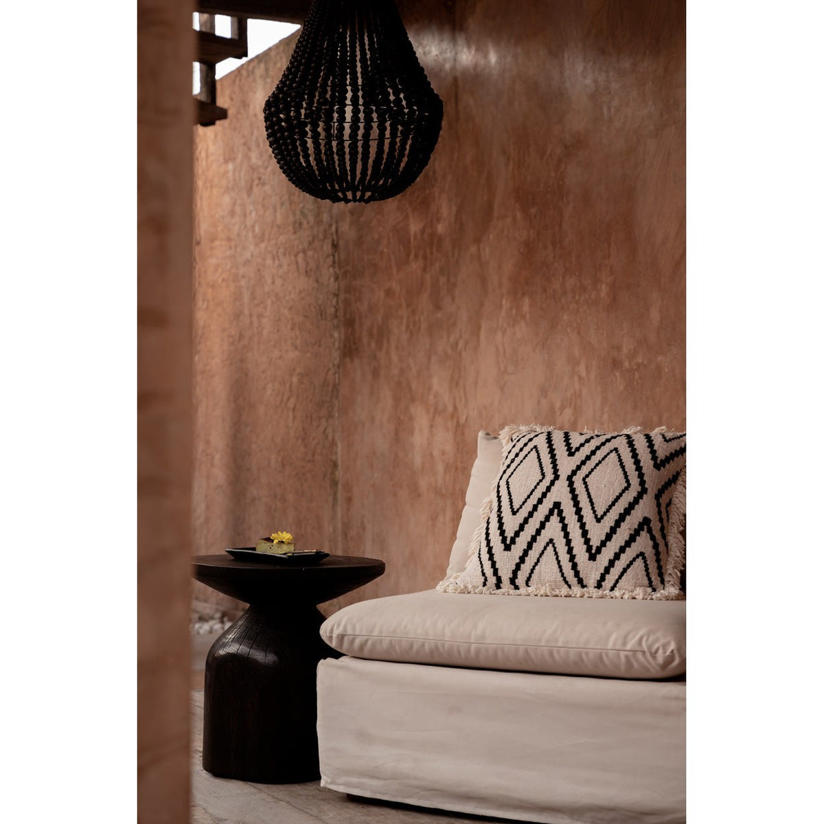 Coin salon avec la housse de coussin Sahara Diamond sur une banquette écrue et une table basse sombre