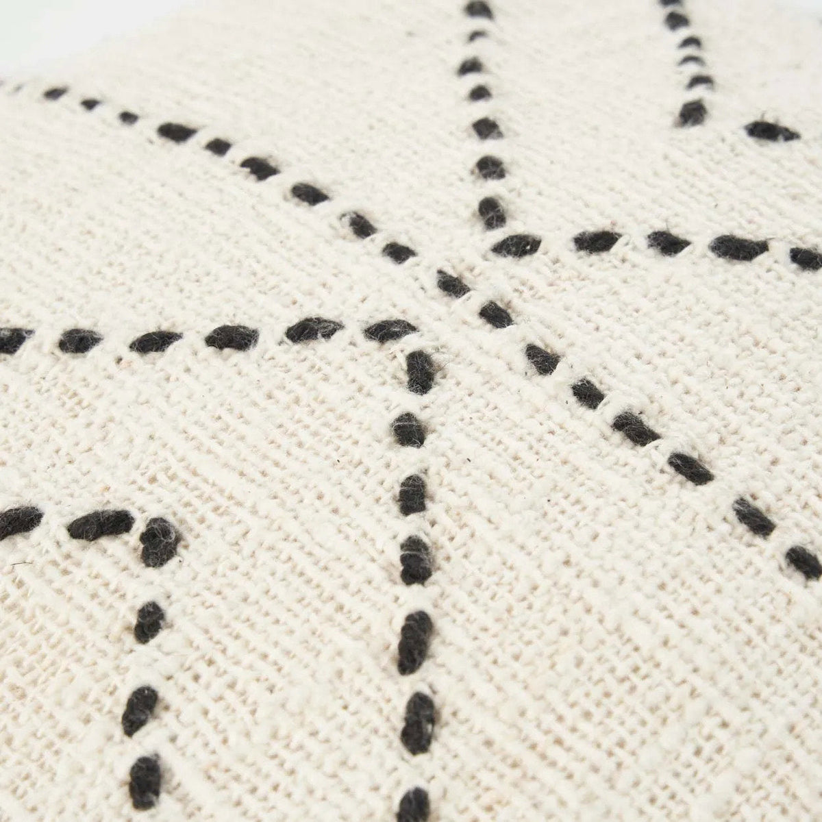 Gros plan sur les points de broderie noirs en relief de la housse Tribal en coton écru