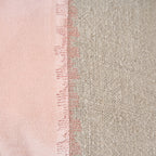Détail de la couture de points roses en créneaux entre le velours rose et le lin naturel