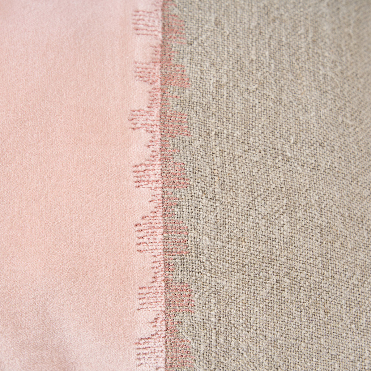 Détail de la couture de points roses en créneaux entre le velours rose et le lin naturel