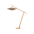 Lampadaire Bali en bambou naturel avec son grand disque tressé de lamelles noires et naturelles au bout du bras