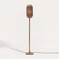 Lampadaire Bhutan allumé sur fond clair, abat-jour cylindrique en bambou tressé naturel et noir sur un pied en bambou