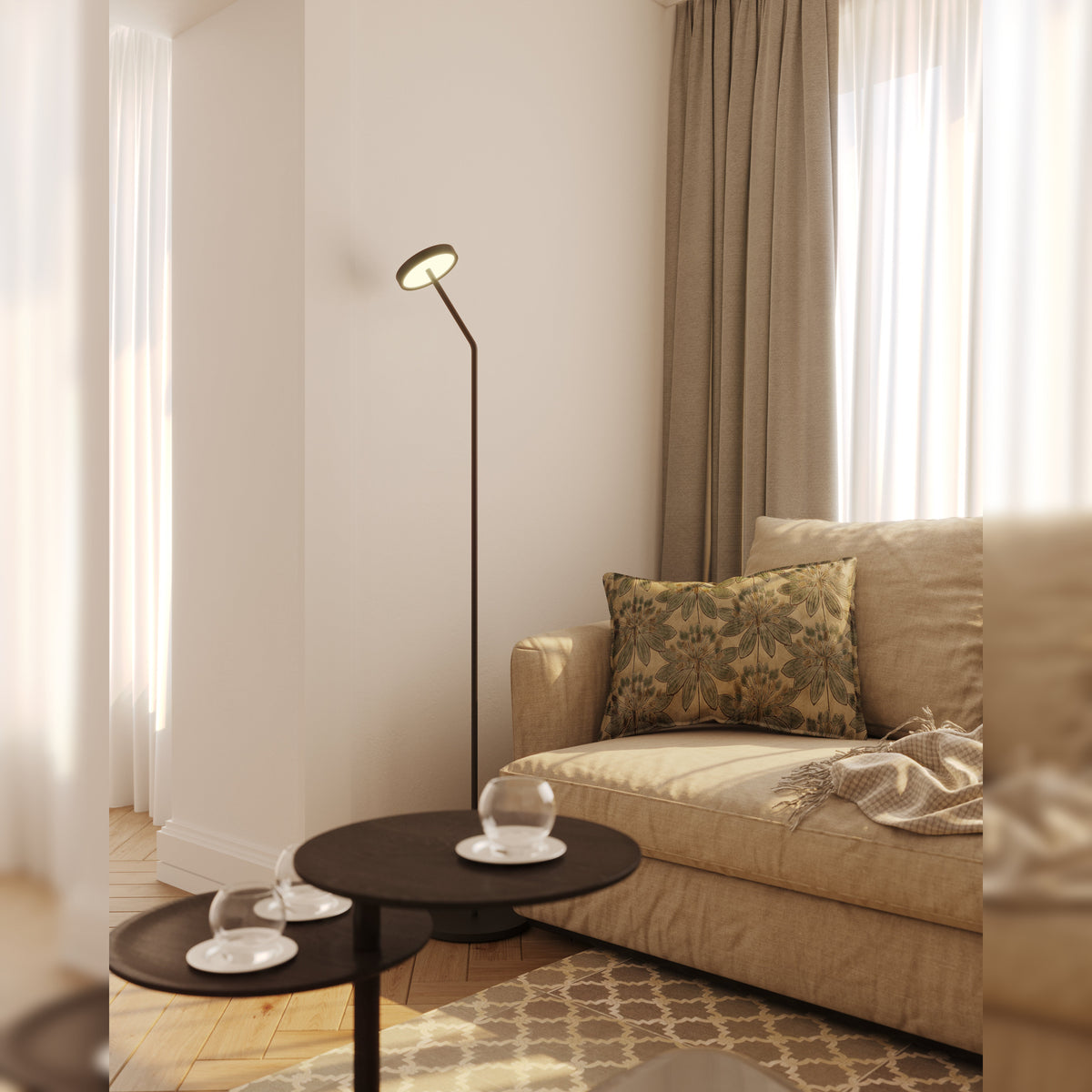 Lampadaire Ibiza noir allumé dans un salon à côté d'un canapé beige et de deux tables basses rondes