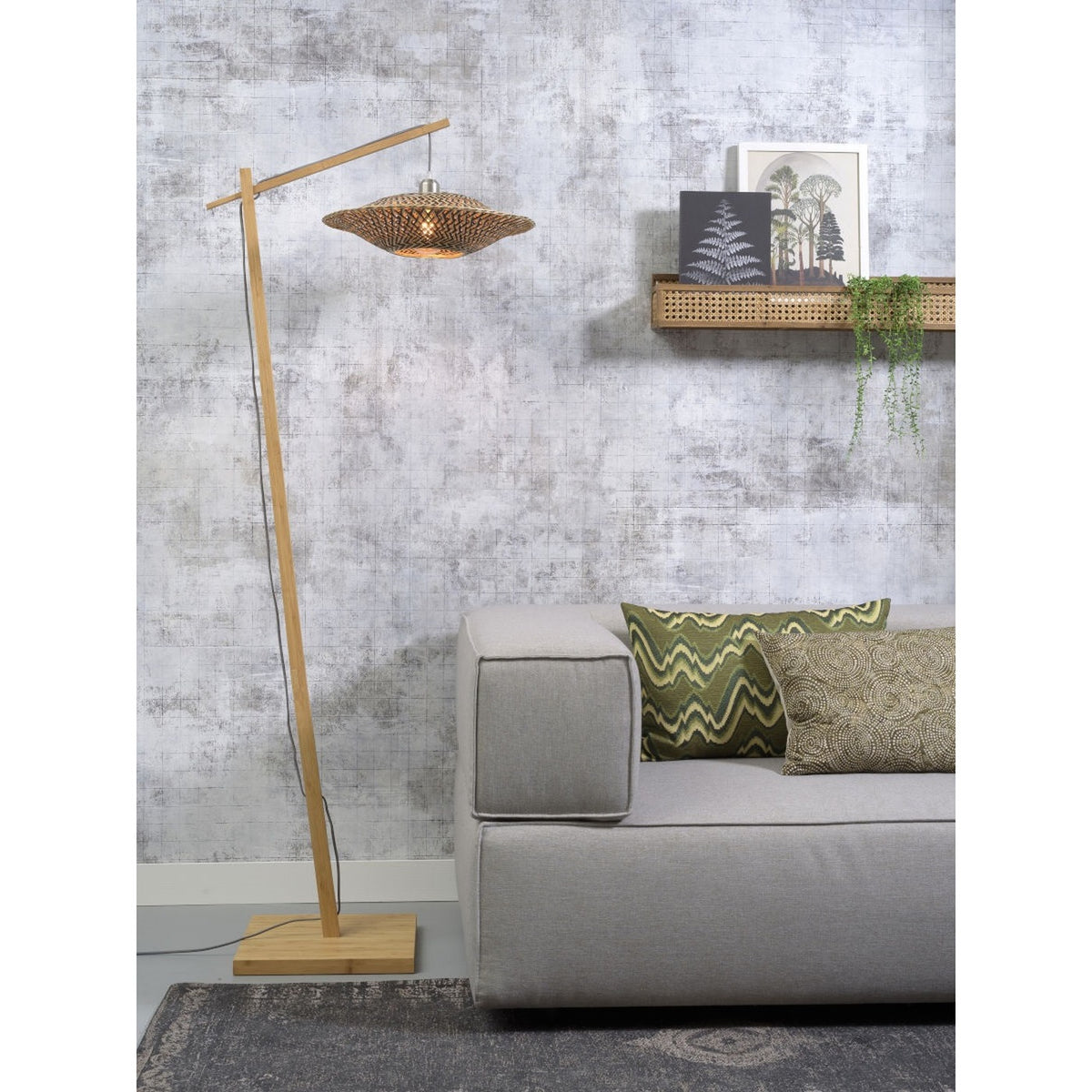 Lampadaire liseuse Bali bambou naturel allumé à côté d'un canapé gris sous une étagère cannée