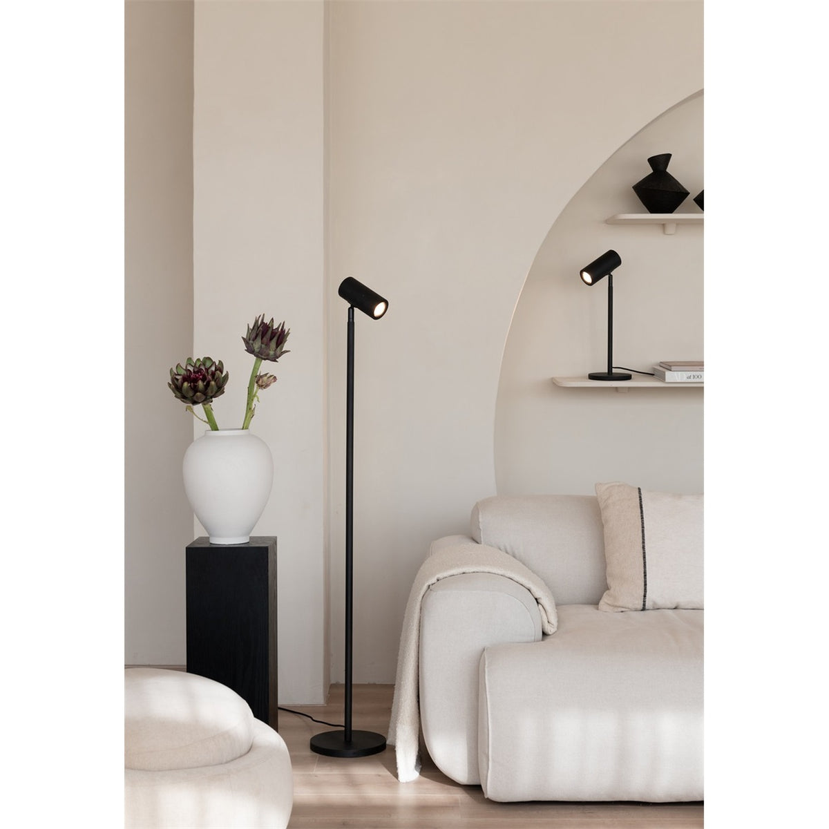 Lampadaire liseuse Java bambou noir près d'un canapé avec une lampe à poser assortie sur l'étagère
