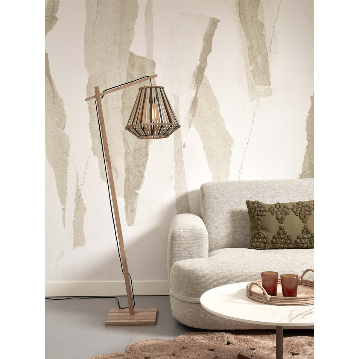 Lampadaire Merapi bambou bicolore à côté d'un canapé crème et d'une table basse ronde sur un tapis en jute