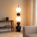 Lampadaire Tama allumé dans l'angle d'un salon entre une console en bois foncé et un canapé beige