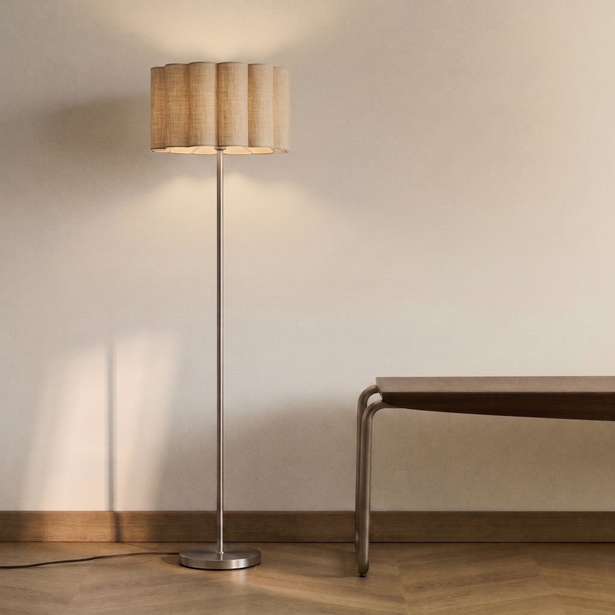 Lampadaire Wattom allumé contre un mur clair, près d'un banc en bois à piètement métallique, sur un parquet à chevrons