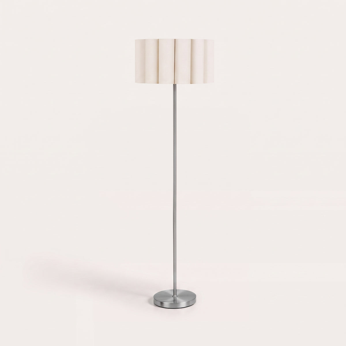 Lampadaire Wattom éteint sur fond clair, abat-jour en lin plissé beige et pied fin en acier brossé