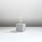 Lampe à poser Ariz en béton brut, cube à ampoule apparente, vue de profil