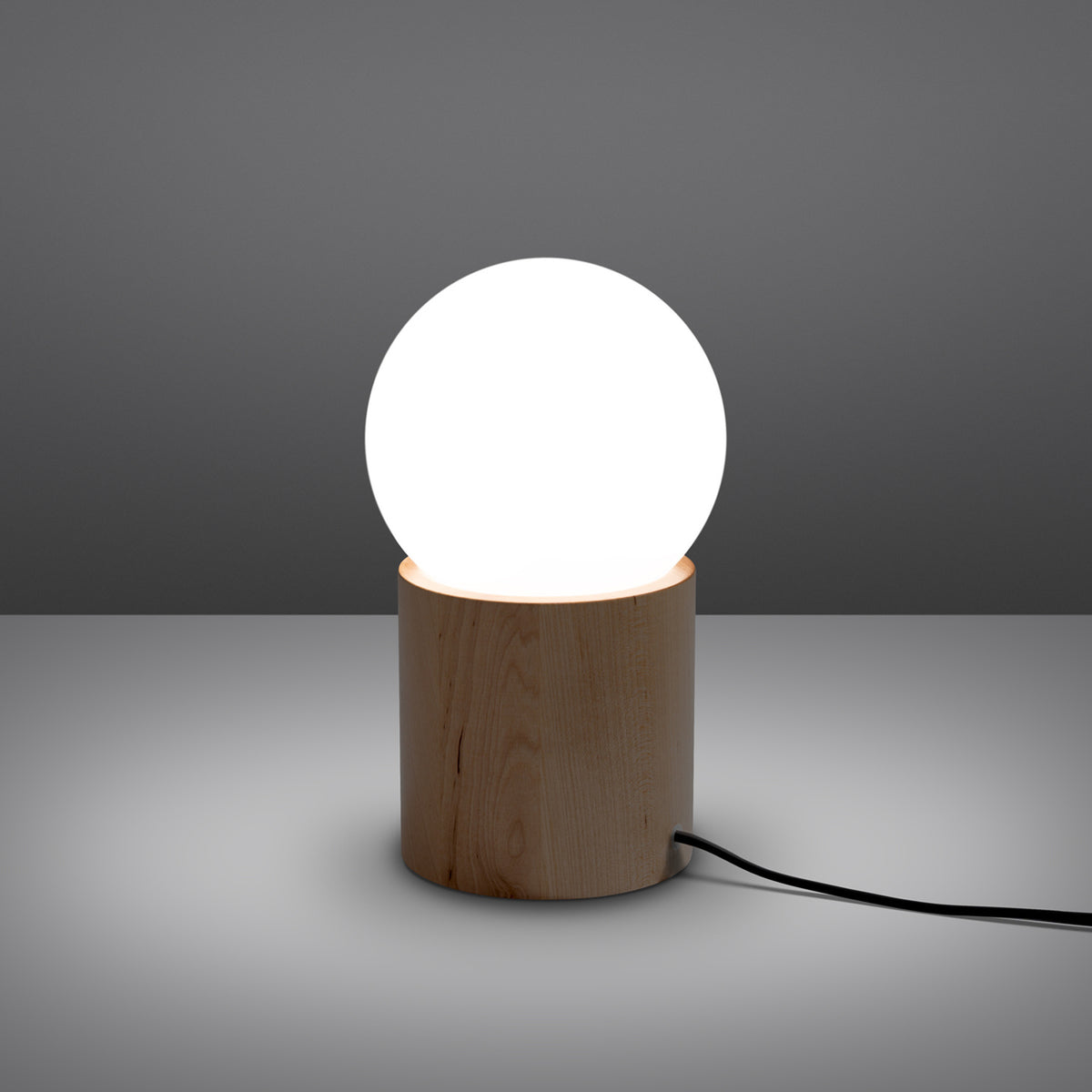 Lampe à poser Boomo allumée avec sa boule opale lumineuse sur le socle en bois