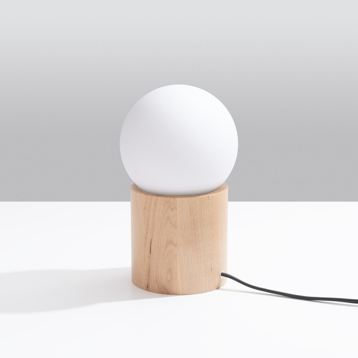 Lampe à poser Boomo éteinte posée sur une table blanche devant un fond gris
