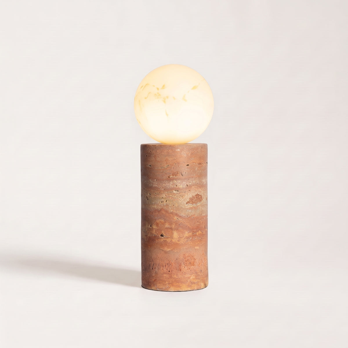 Lampe à poser Tivoli, socle en travertin terracotta aux veines rouges et globe en verre veiné allumé