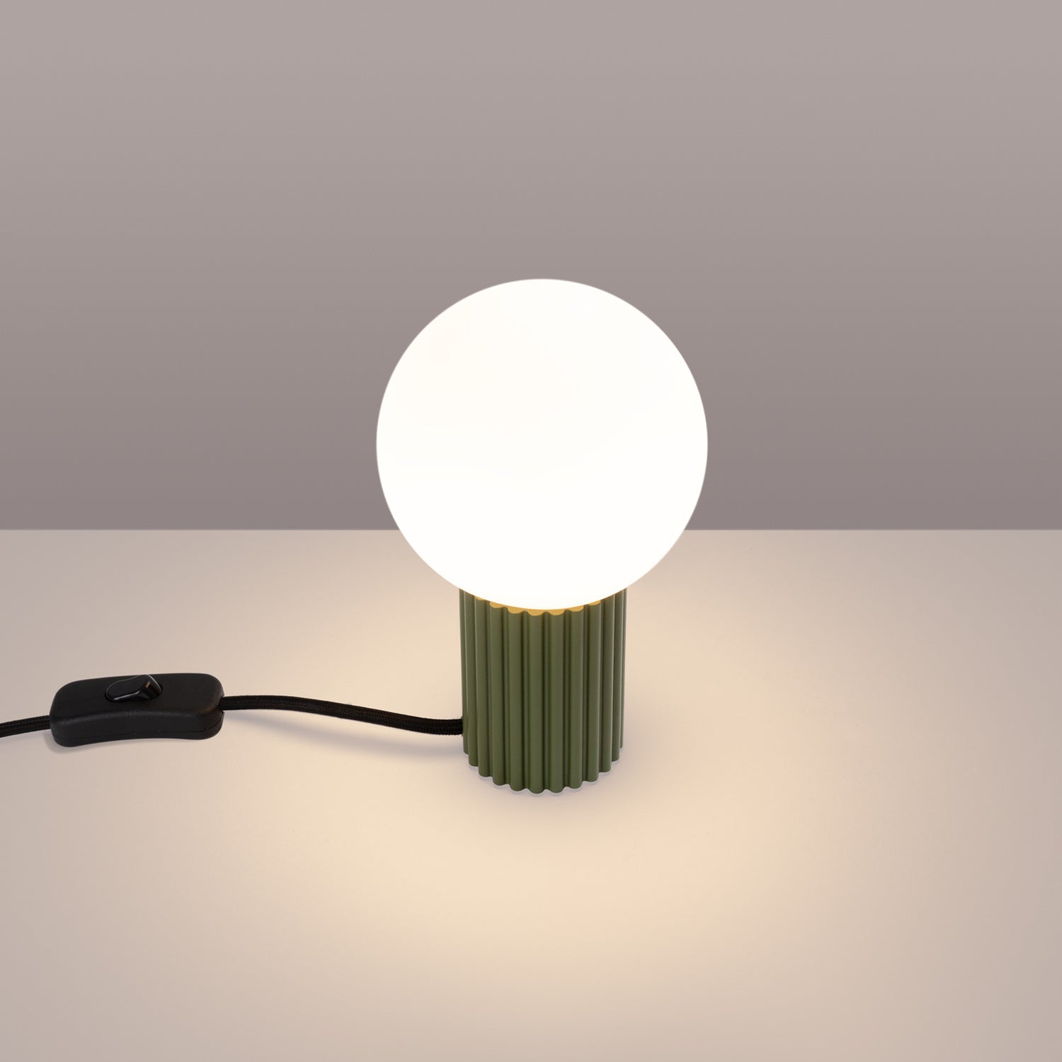 Lampe à poser Halo boule opale vert olive allumée, lumière basse et diffuse
