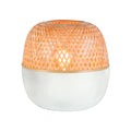 Lampe à poser Mekong allumée avec son dôme en bambou tressé sur une base blanche arrondie sur fond blanc