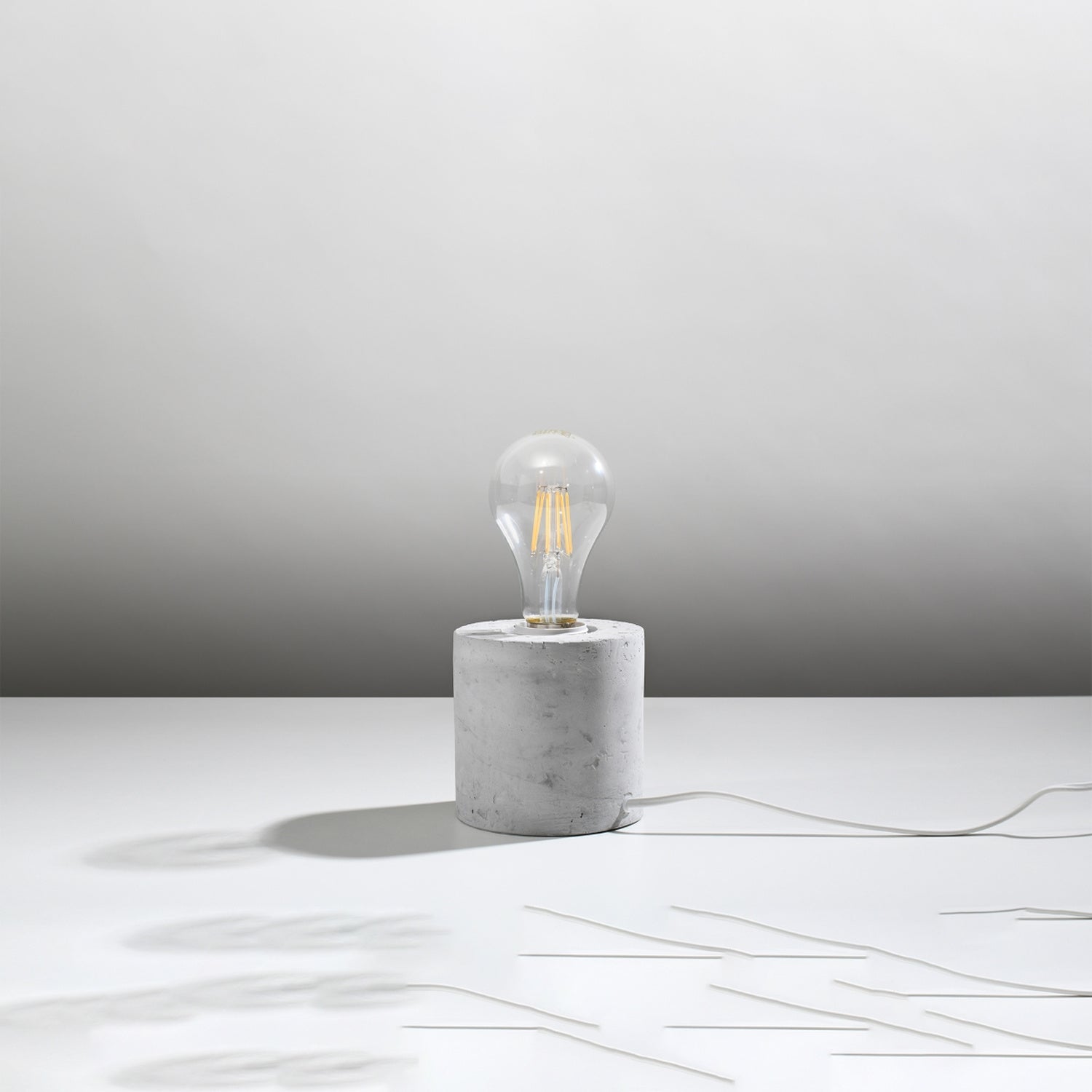 Lampe à poser Salgado en béton brut, cylindre à ampoule apparente, vue de profil