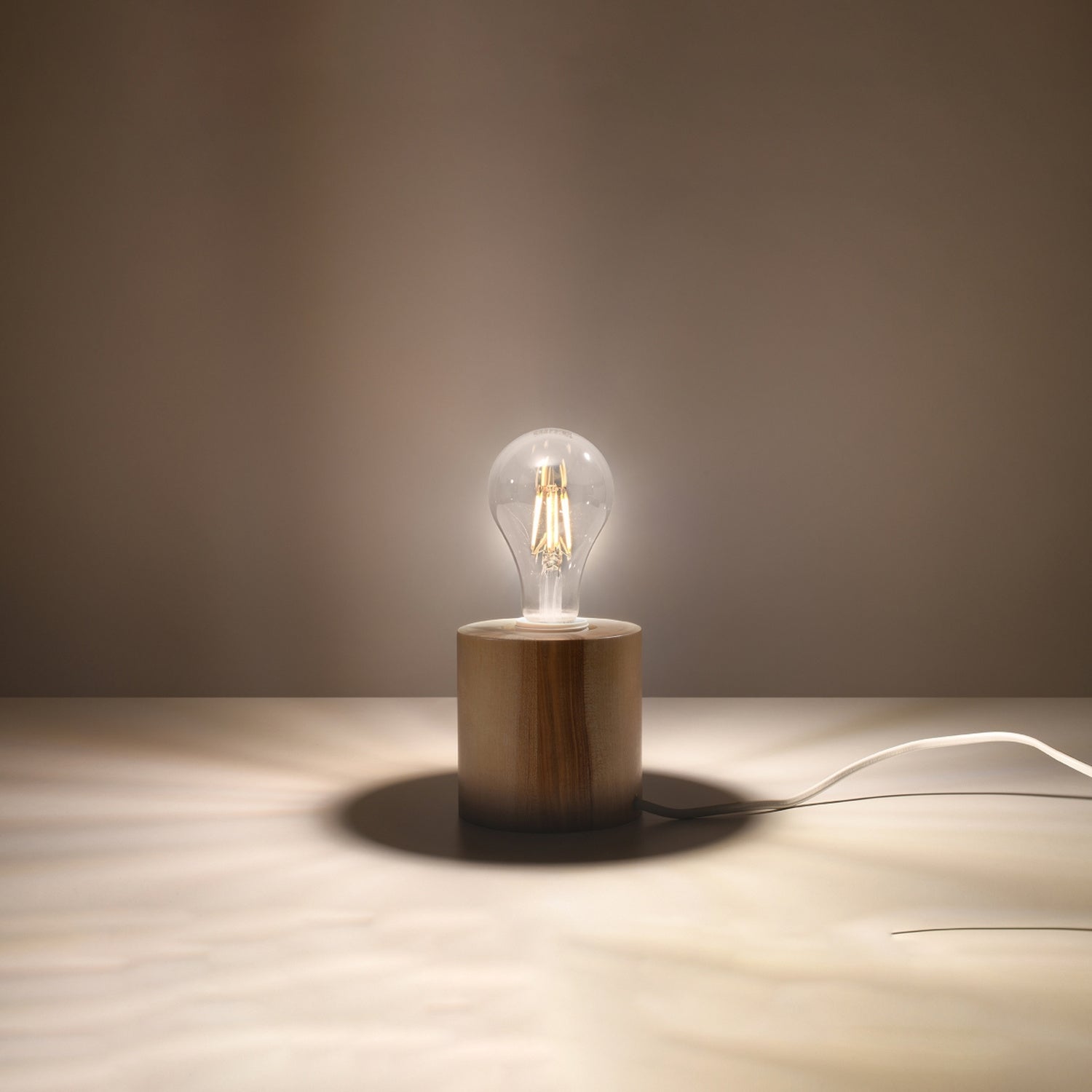 Lampe à poser Salgado en bois naturel, cylindre massif à ampoule apparente, ampoule allumée