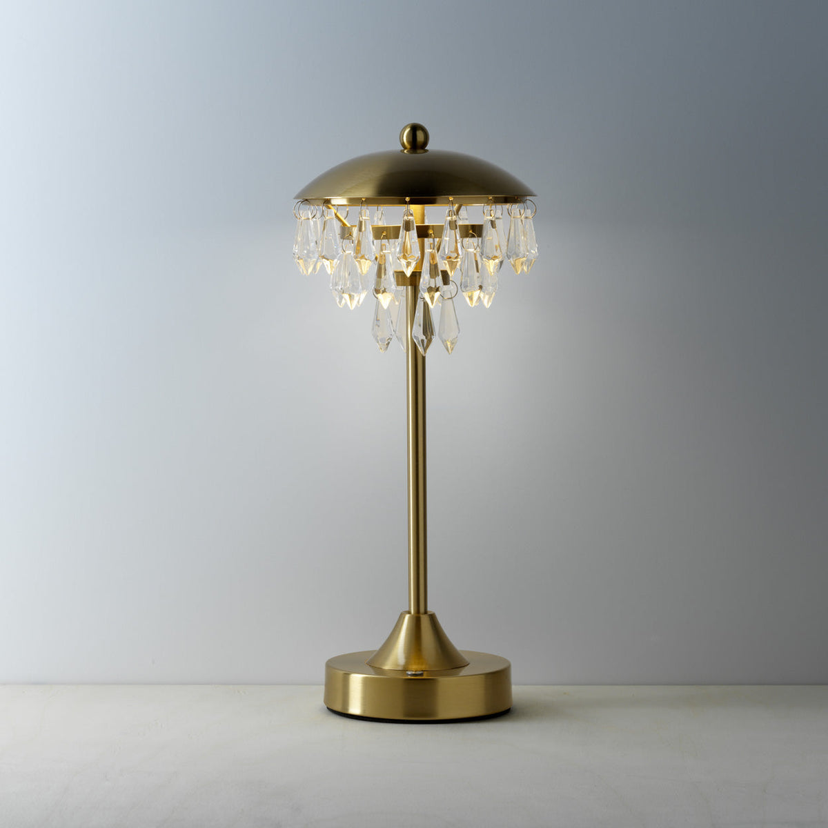 Lampe Chandelette allumée avec une lueur ambrée sous la coupole et les pampilles qui s'illuminent