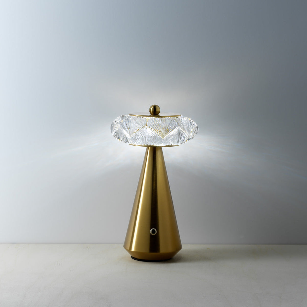 Lampe Diamond Diva allumée en lumière blanche devant un mur gris