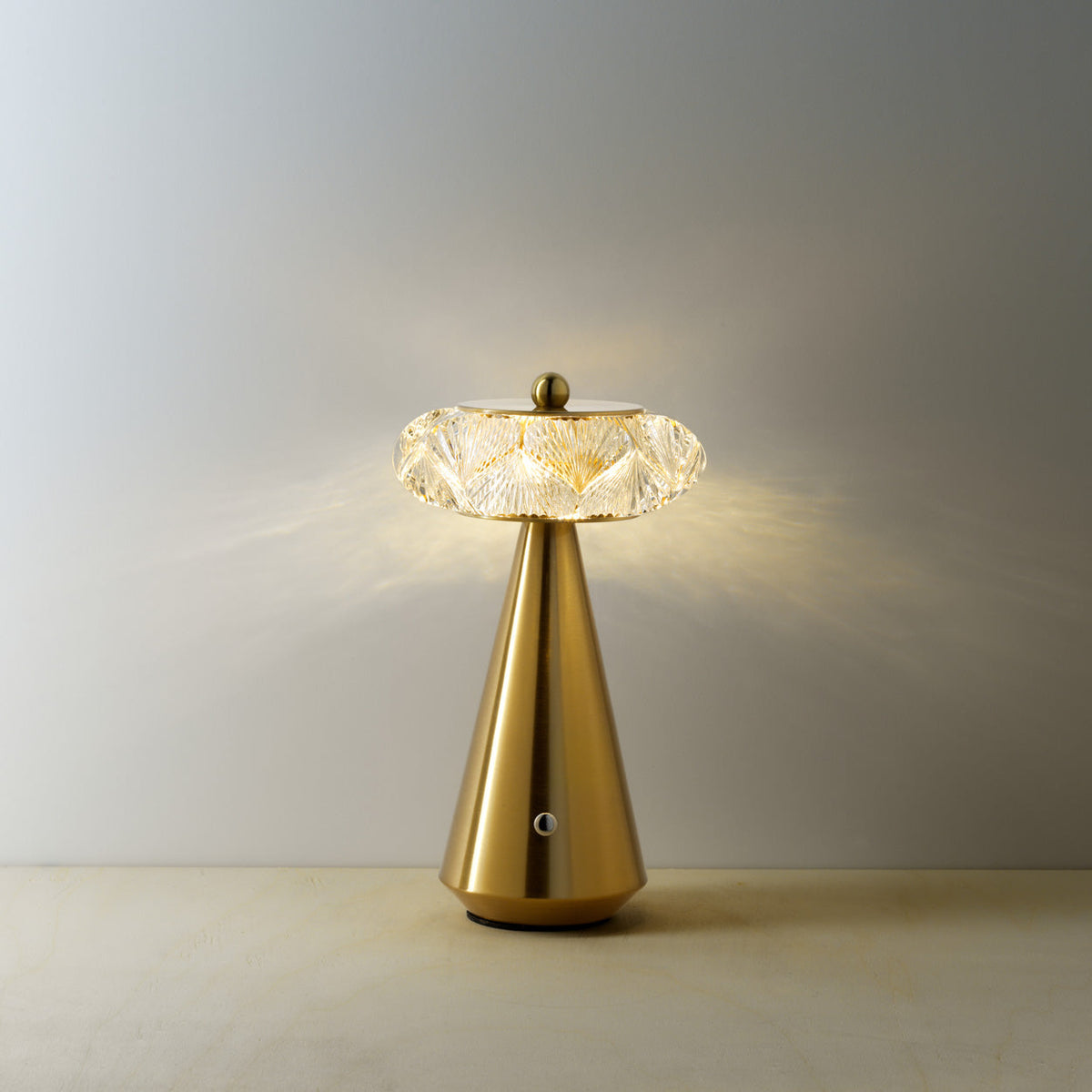 Lampe Diamond Diva allumée en lumière chaude projetant des reflets sur un mur clair