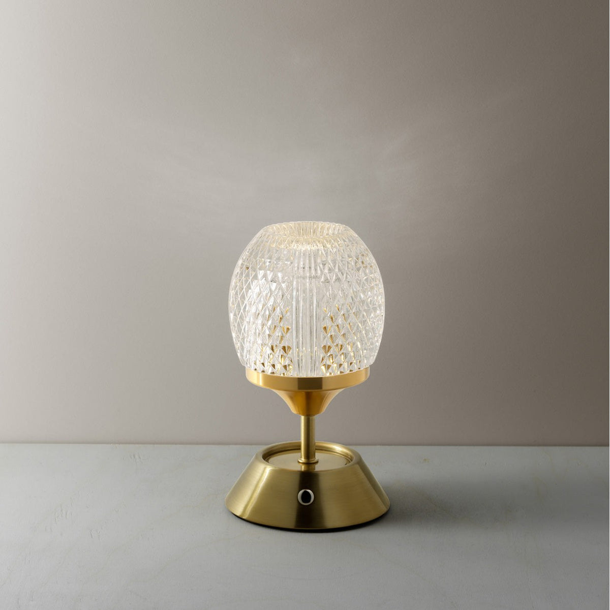 Lampe Glow Sinatra allumée en lumière chaude sur une table grise